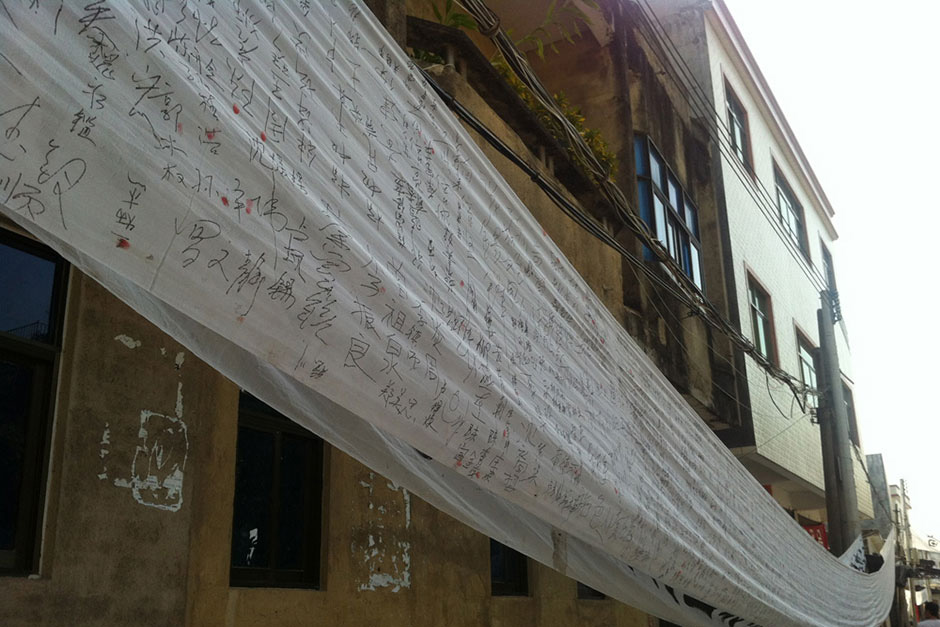 A banner hangs along the city street with villagers’ signatures petitioning government officials at higher levels.
